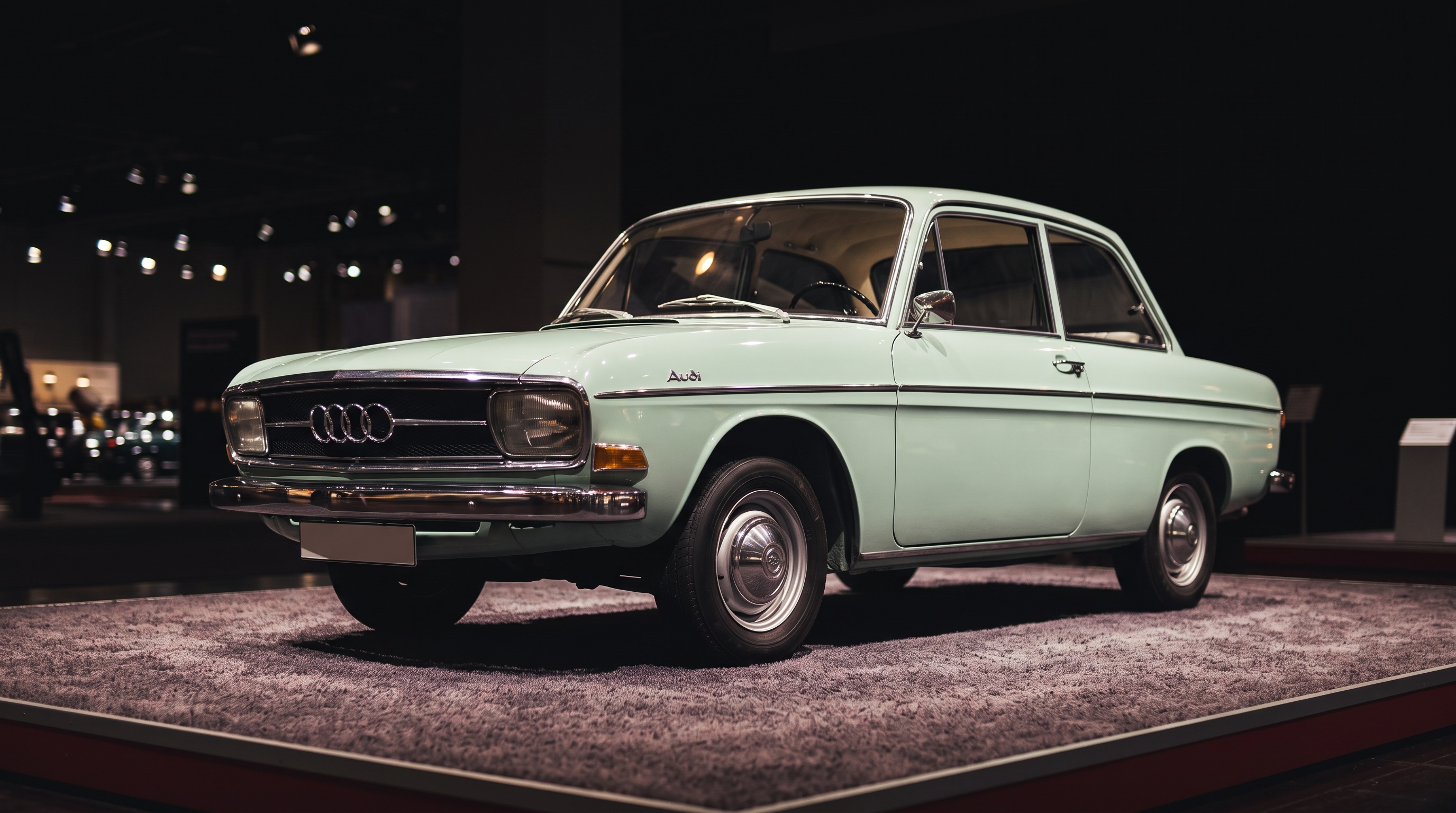 A pale green 1965 Audi F103 two-door saloon on a motor-show display platform