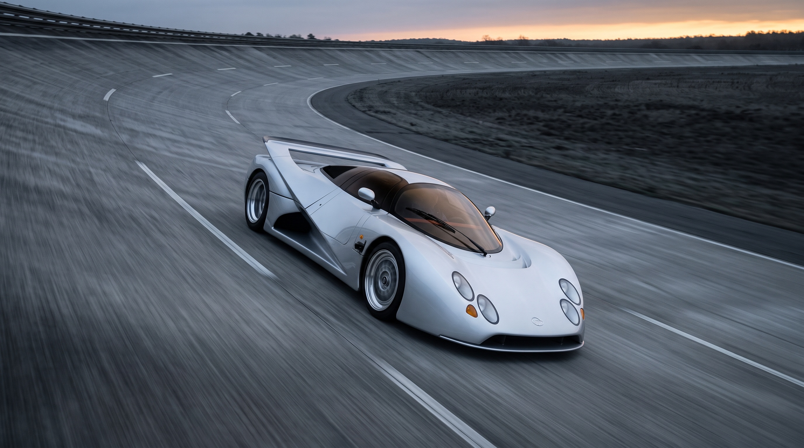 The silver Lotec C1000 sweeping through a high-speed banked test circuit