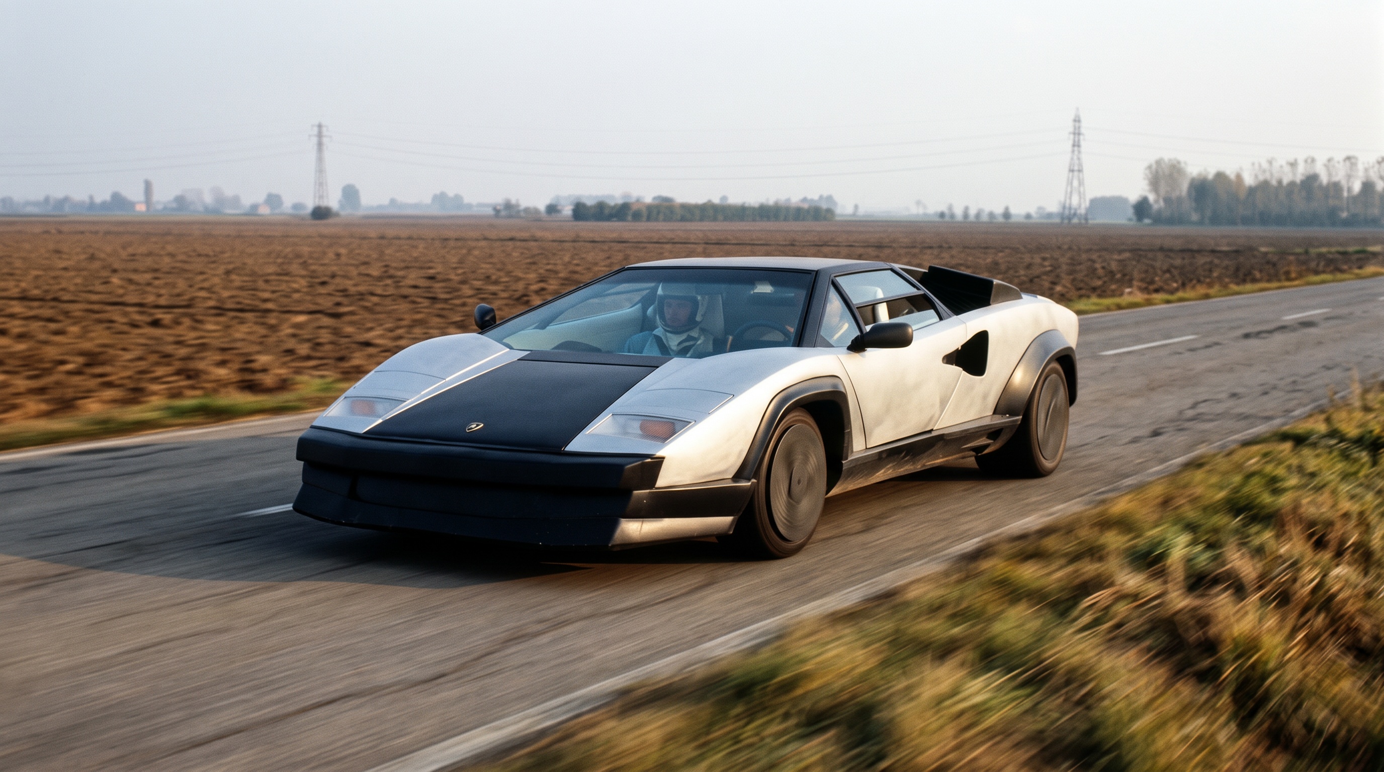未经喷漆的银灰色 Lamborghini Countach Evoluzione 原型车,在两侧是翻耕农田的乡间道路上疾驰