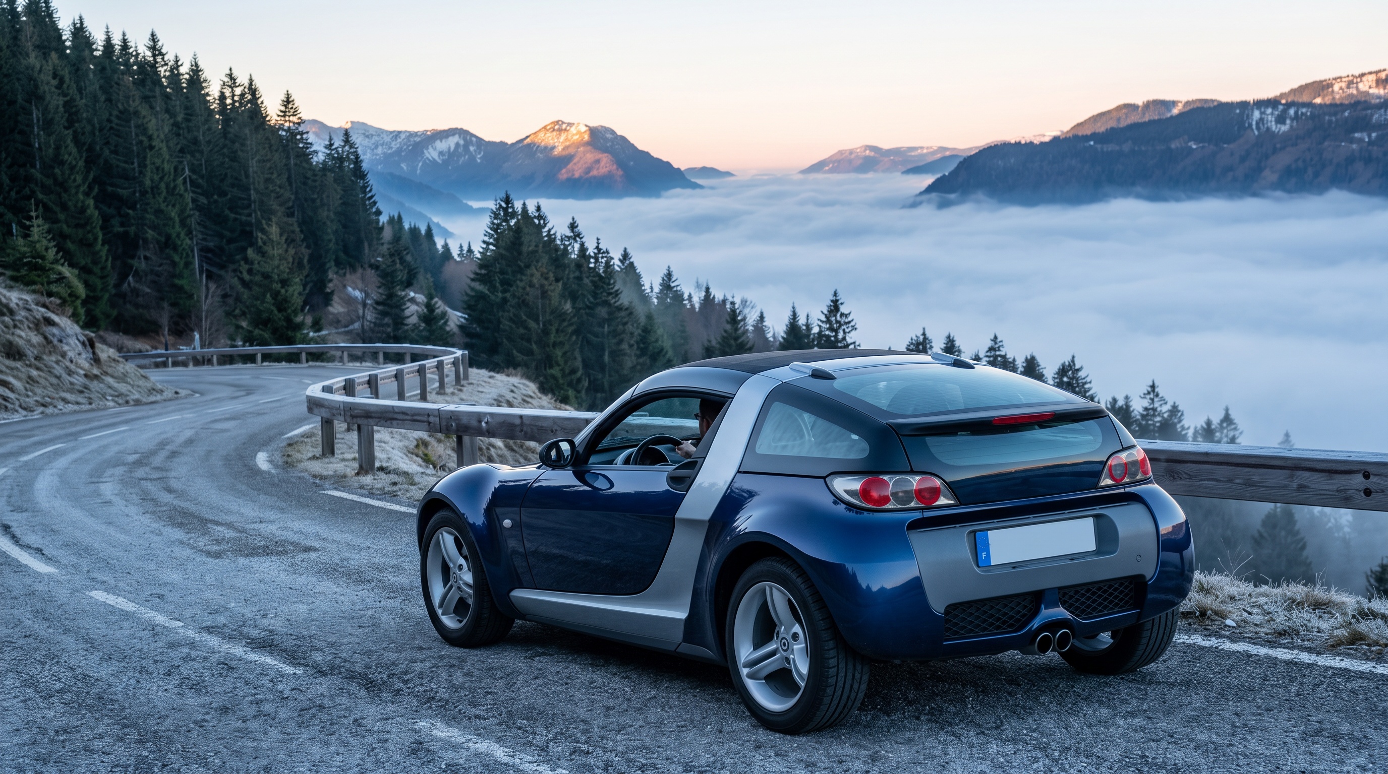 Un smart roadster-coupé azul oscuro en un puerto alpino sobre un mar de nubes